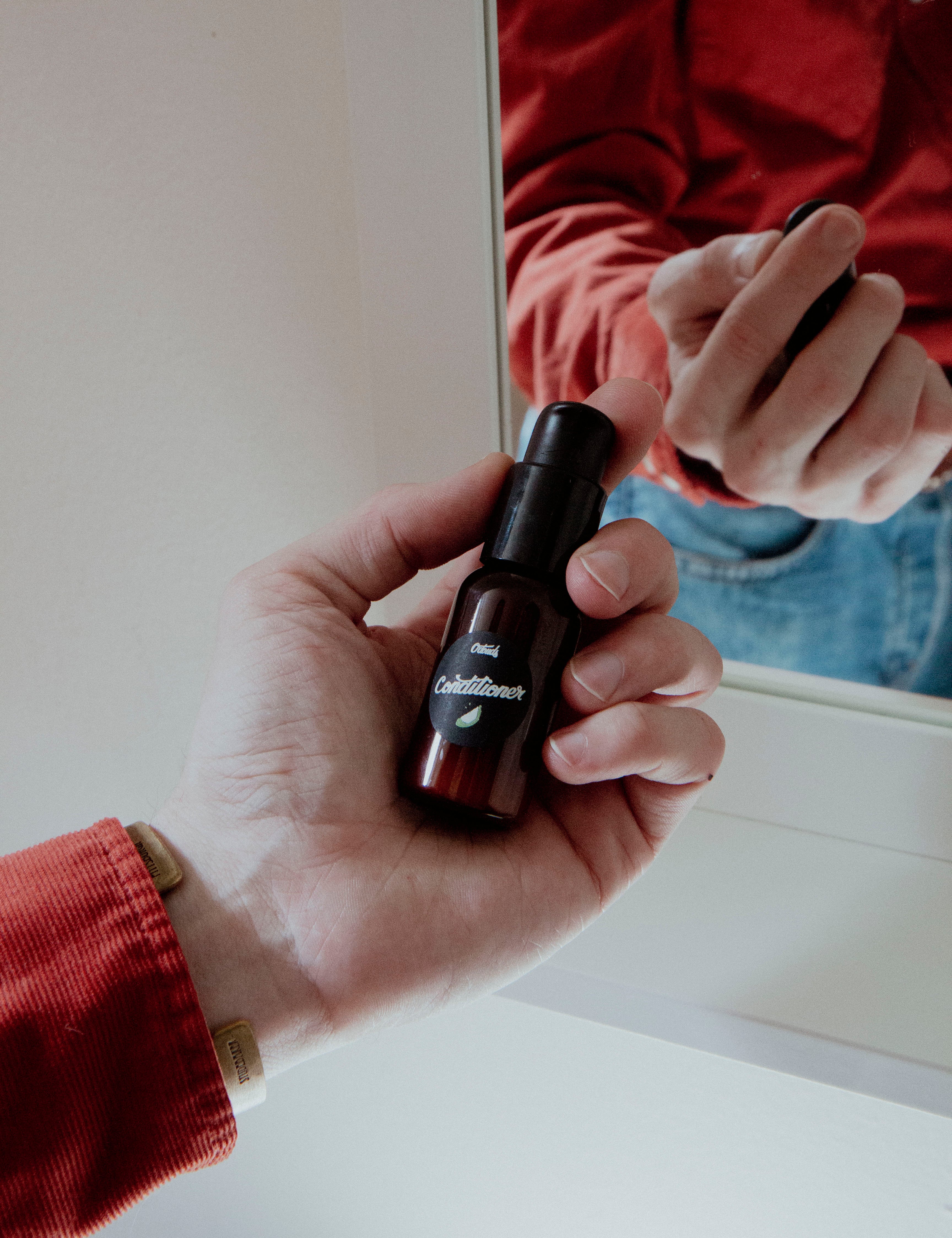 Holding small Tea Tree and Grapefruit Conditioner Sample in bathroom reflection