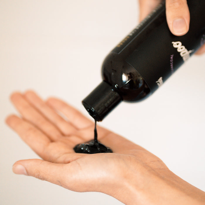 Lavender and peppermint scented black shampoo bottle pouring into outstretched hand